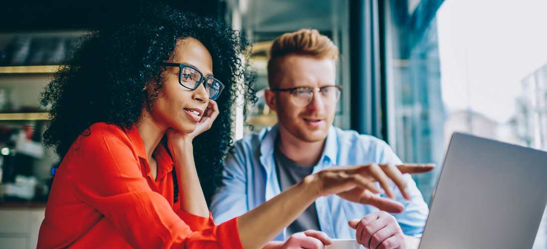 Vrouwelijke en mannelijke collega samen aan het werk achter één computerscherm.